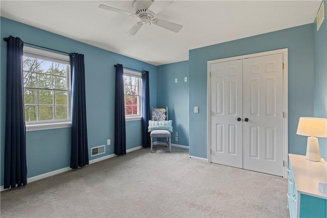 living area with light colored carpet, a ceiling fan, and baseboards