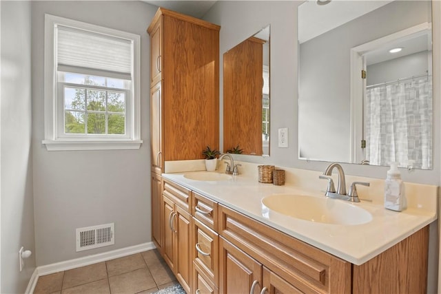 bathroom with double vanity, tile patterned floors, and baseboards