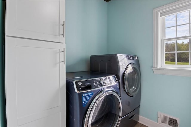 laundry area featuring separate washer and dryer, baseboards, and cabinet space