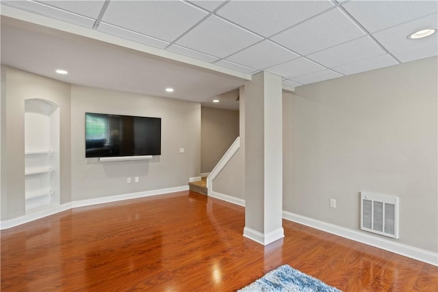unfurnished living room featuring wood finished floors, stairway, recessed lighting, baseboards, and built in shelves
