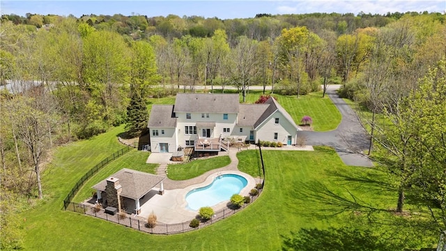 aerial view of property and surrounding area with a pool and a heavily wooded area