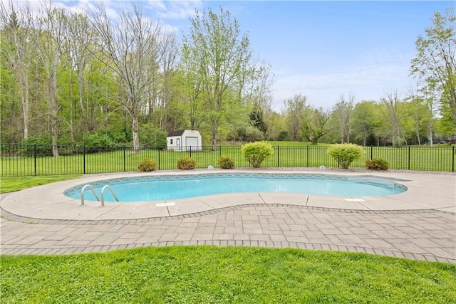 view of swimming pool featuring a patio area, an outbuilding, and a storage shed