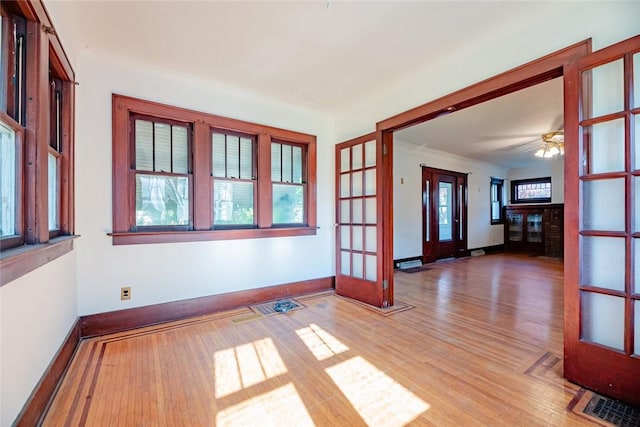 empty room featuring wood finished floors, baseboards, french doors, and crown molding