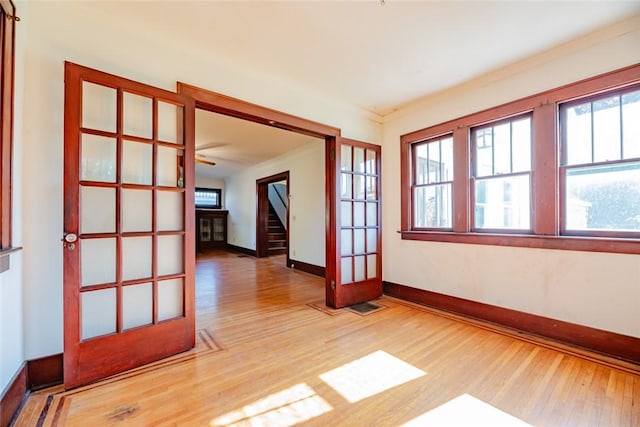spare room featuring light wood finished floors, baseboards, healthy amount of natural light, and ornamental molding