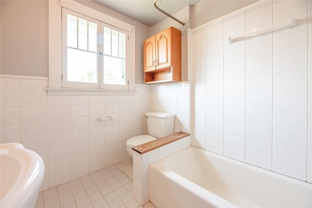 bathroom featuring tile walls, toilet, and a tub to relax in