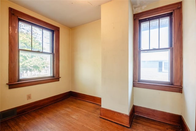 spare room with wood finished floors, plenty of natural light, and baseboards
