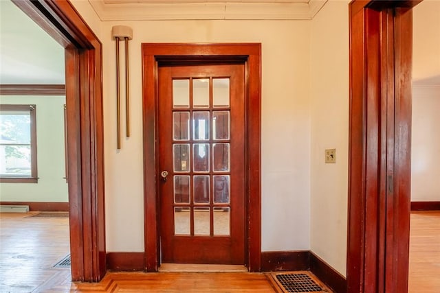 doorway to outside with ornamental molding, baseboards, and wood finished floors