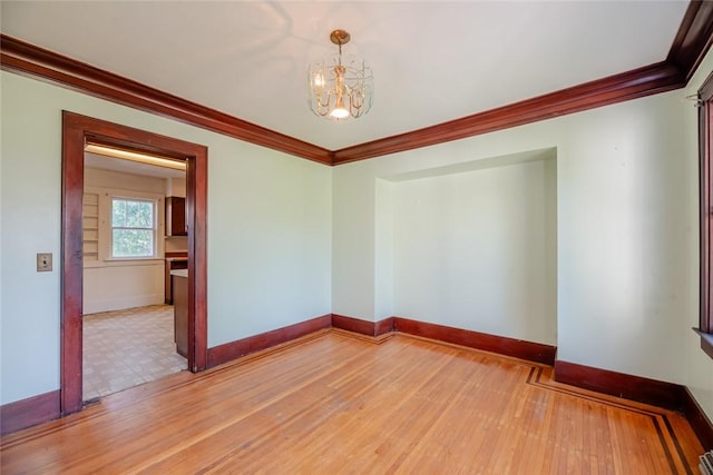 unfurnished room with a chandelier, ornamental molding, baseboards, and light wood-style floors