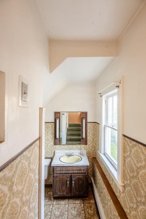 half bath with vanity, wainscoting, toilet, and tile walls