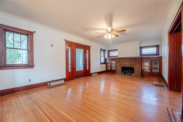 unfurnished living room featuring light wood finished floors, healthy amount of natural light, baseboards, and crown molding