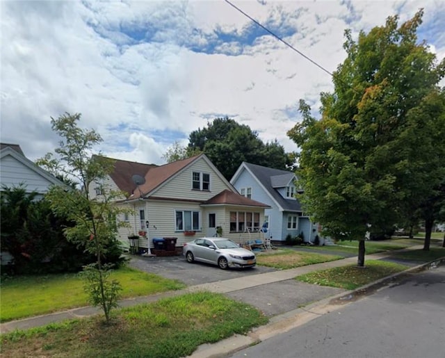 bungalow featuring asphalt driveway and a front yard