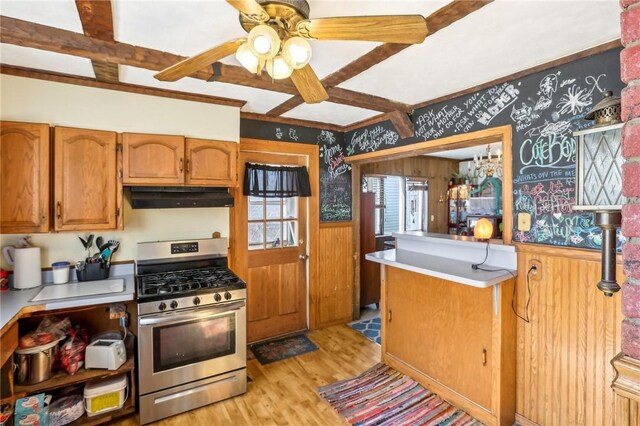136 Summit St, Batavia-City, NY 14020 - kitchen with stainless steel gas stove, under cabinet range hood, wainscoting, wallpapered walls, and light wood-style floors