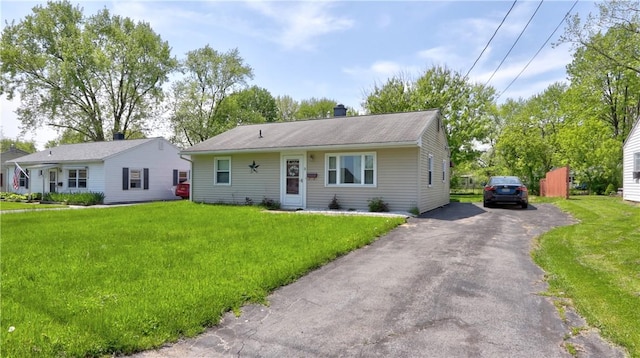 view of front of home featuring a front lawn, a chimney, and driveway