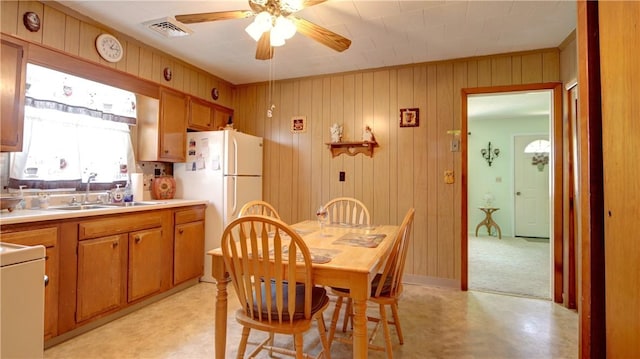dining space featuring a ceiling fan, light flooring, and wood walls