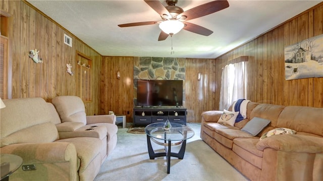 living room featuring wooden walls, carpet flooring, and a ceiling fan