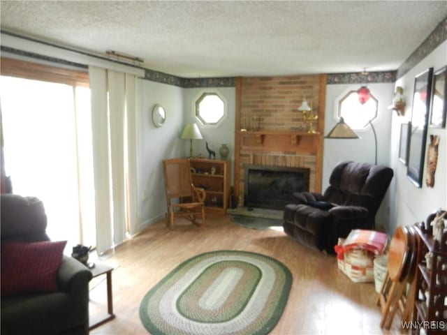 living room with a textured ceiling, wood finished floors, and a fireplace