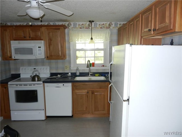 kitchen with white appliances, a sink, dark countertops, wallpapered walls, and a textured ceiling