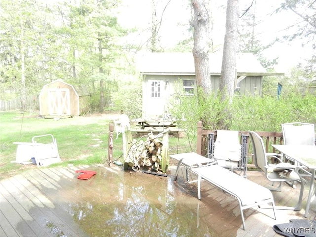 view of patio / terrace featuring outdoor dining space, a deck, a storage unit, and an outdoor structure