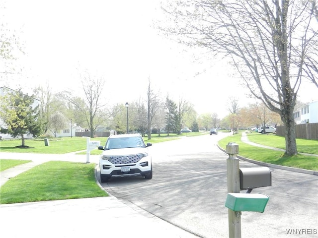 view of asphalt road featuring sidewalks, a residential view, and curbs