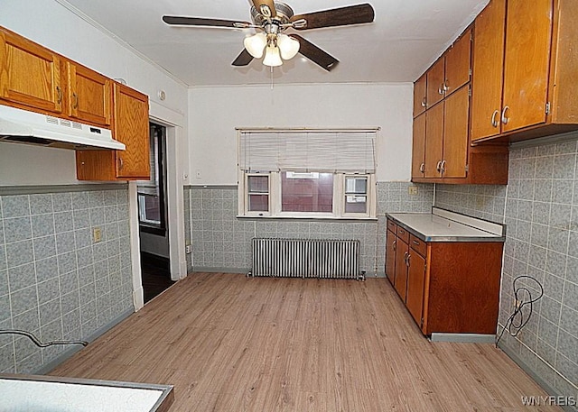 54 Pine Ridge Rd, Cheektowaga, NY 14211 - kitchen featuring tile walls, radiator, under cabinet range hood, brown cabinetry, and ceiling fan