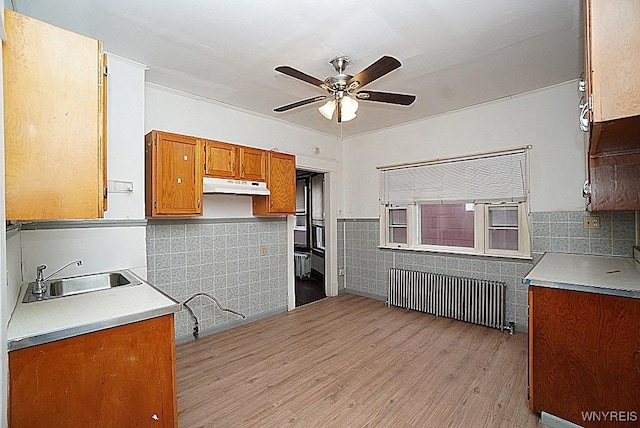 54 Pine Ridge Rd, Cheektowaga, NY 14211 - kitchen with radiator heating unit, a sink, a ceiling fan, brown cabinetry, and under cabinet range hood