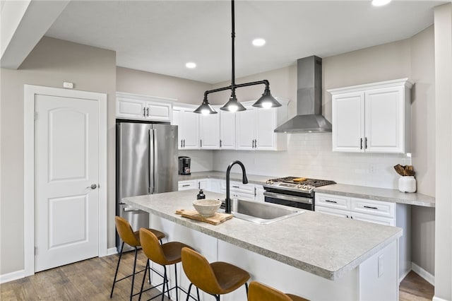 kitchen with wall chimney range hood, stainless steel appliances, a sink, a breakfast bar, and decorative backsplash