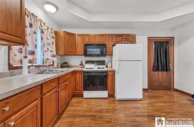 kitchen featuring white appliances, a sink, light wood-style floors, and light countertops
