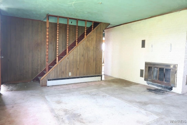 5910 Porter Rd, Niagara, NY 14304 - unfurnished living room featuring baseboard heating, stairs, concrete flooring, a fireplace, and wood walls