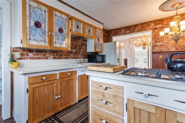 187 Clark St, Canandaigua-City, NY 14424 - kitchen with a chandelier, a sink, light countertops, brick wall, and stainless steel gas cooktop