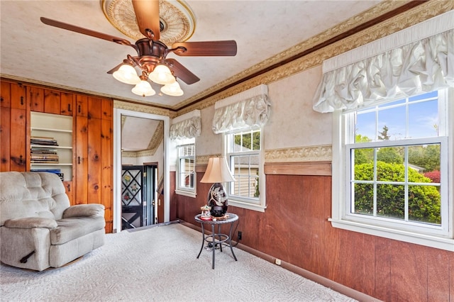 187 Clark St, Canandaigua-City, NY 14424 - sitting room featuring carpet, wooden walls, crown molding, and a ceiling fan