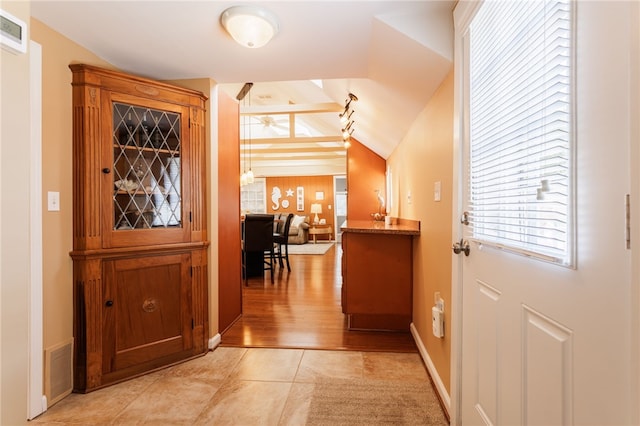 entryway featuring lofted ceiling, baseboards, and light wood-style flooring