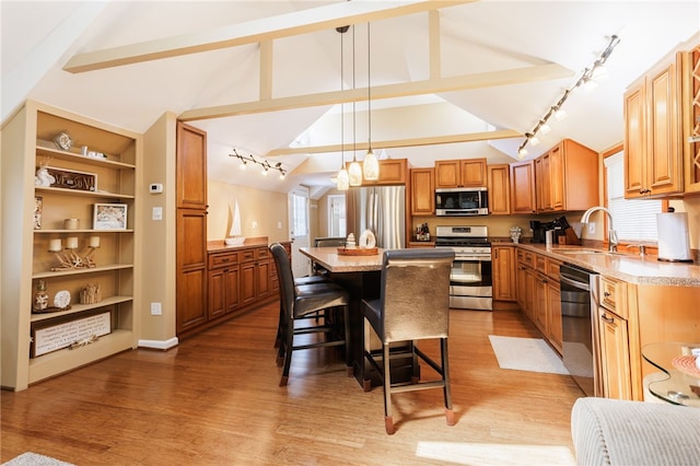 kitchen featuring appliances with stainless steel finishes, a sink, a kitchen breakfast bar, a center island, and track lighting