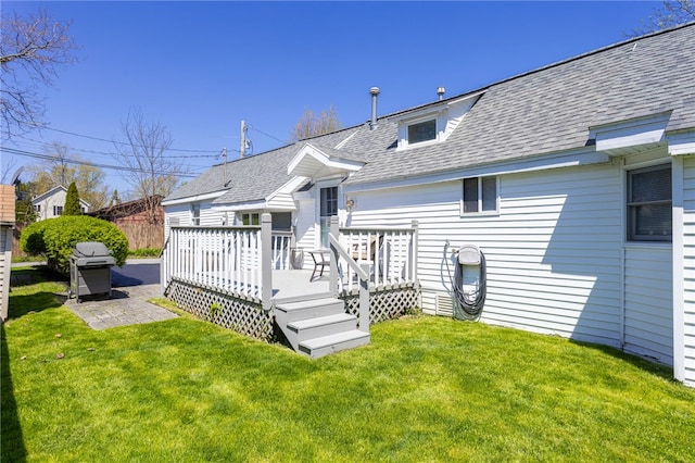 back of property featuring roof with shingles, a yard, and a wooden deck