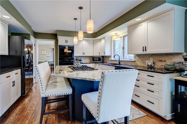 kitchen featuring a sink, black appliances, decorative backsplash, white cabinetry, and recessed lighting
