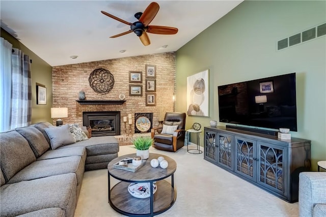 carpeted living room with vaulted ceiling, ceiling fan, and a brick fireplace
