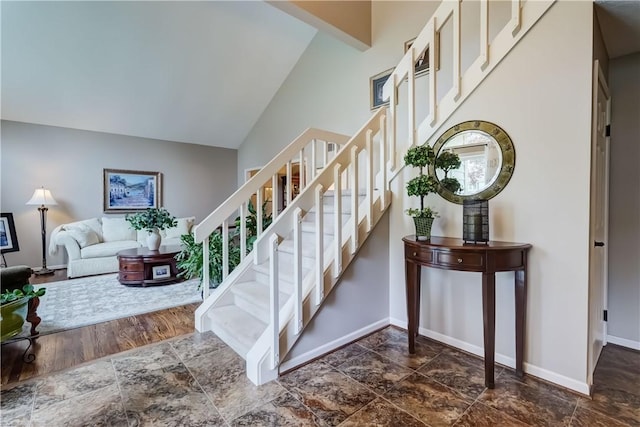 stairs featuring baseboards and high vaulted ceiling