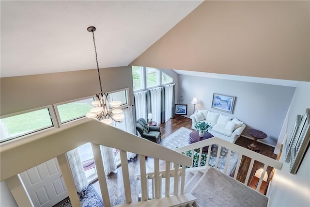 stairway featuring a chandelier, wood finished floors, and vaulted ceiling