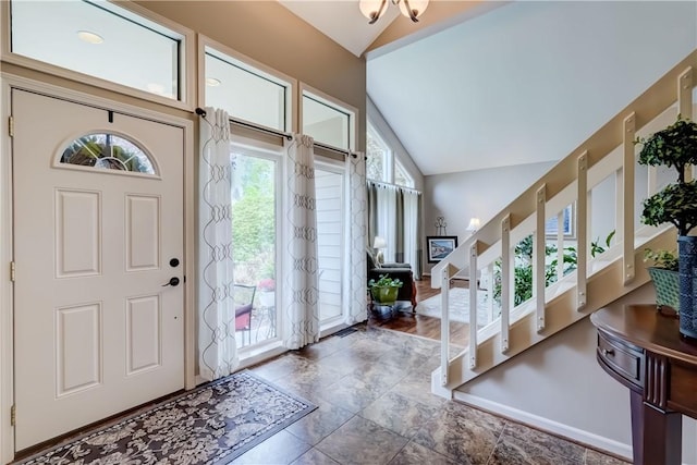 entrance foyer featuring lofted ceiling, healthy amount of natural light, and stone finish floors