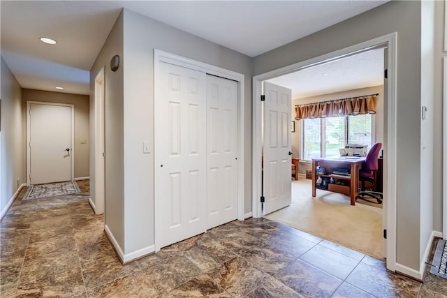 hallway with a desk, baseboards, carpet, recessed lighting, and stone finish floors