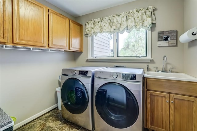 clothes washing area featuring separate washer and dryer, cabinet space, and baseboards
