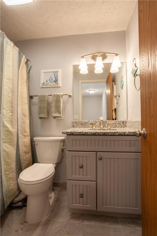 full bath featuring toilet, a textured ceiling, vanity, tile patterned floors, and a shower with curtain