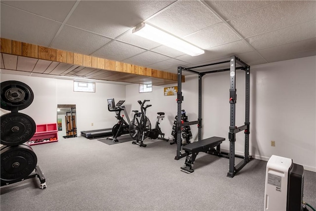 workout room featuring a drop ceiling, carpet flooring, and baseboards