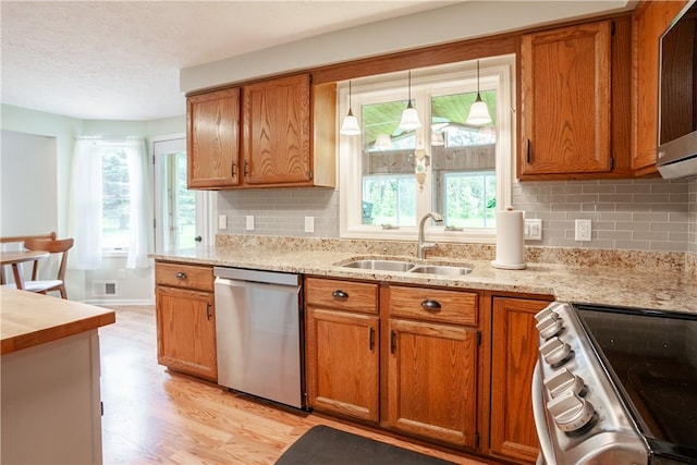 kitchen with stainless steel appliances, a sink, brown cabinets, and a textured ceiling