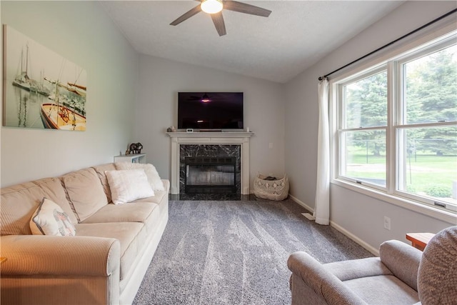 living area featuring lofted ceiling, ceiling fan, a fireplace, and carpet
