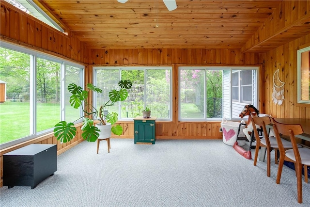 sunroom / solarium with vaulted ceiling, wooden ceiling, carpet floors, wood walls, and ceiling fan