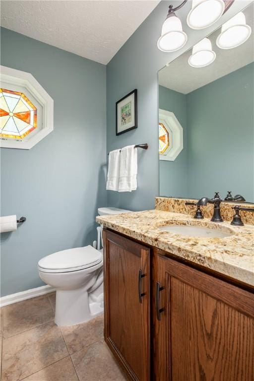 bathroom featuring toilet, vanity, baseboards, and tile patterned flooring