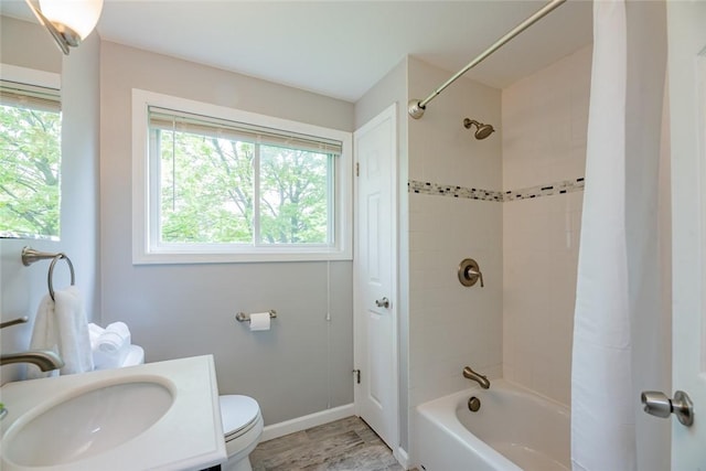 full bathroom featuring plenty of natural light, toilet, shower / tub combo with curtain, and baseboards