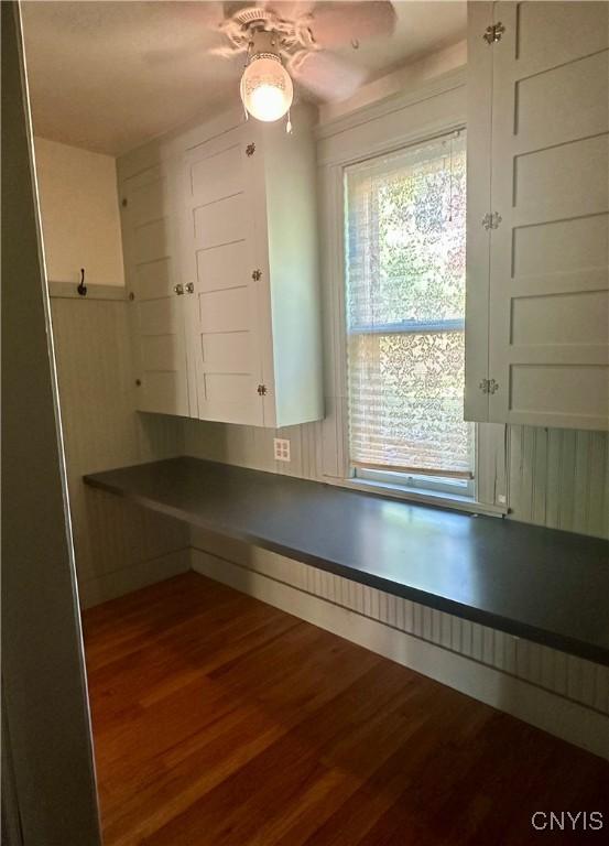 923 Teall Ave, Syracuse, NY 13206 - kitchen with wood finished floors, dark countertops, a ceiling fan, and white cabinets