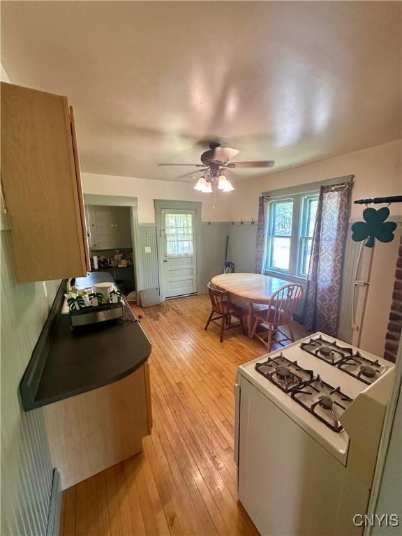 923 Teall Ave, Syracuse, NY 13206 - kitchen with white gas range oven, light wood-style floors, a ceiling fan, and dark countertops