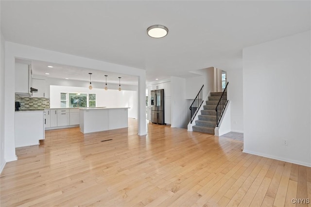 5761 Chantilly Ct, Manlius, NY 13057 - unfurnished living room featuring light wood-style floors, stairs, and baseboards